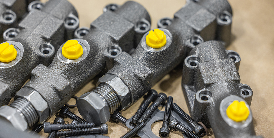 Hydraulic pump components with yellow caps and bolts.